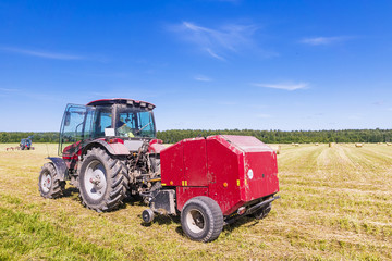 Red tractor in the field on a hay