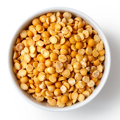 Dry yellow split peas in white ceramic bowl isolated on white.