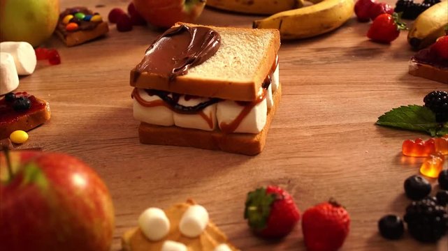 CLOSE UP FOOD: crazy sweet sandwich with candies, fruits, nutella and milk on a black background 
