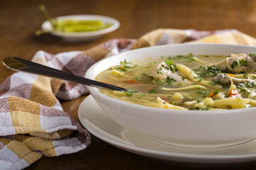 Chicken soup with noodles and fresh vegetables in bowl with spoo