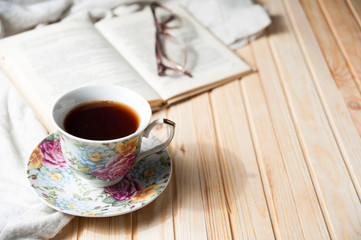 cup of coffee or tea on wooden table with open book