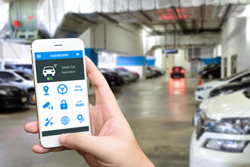 Auto park , pick me up , auto drive and internet of things (iots) in smart car concept. Hand holding smart phone and application dashboard with blur car parking background