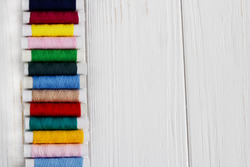 a lot of color threads on white wooden table. background