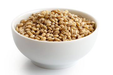 Dry pearl barley in white ceramic bowl isolated on white.