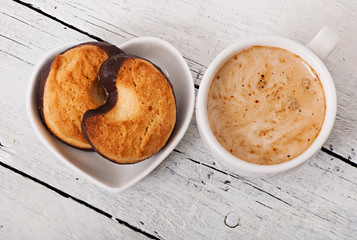 Cup of coffee and delicious baked cookies on old wooden background.