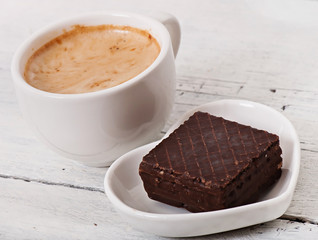 Cup of coffee and delicious baked cookies on old wooden background.