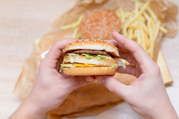 fast food, people and unhealthy eating concept - close up of man hands holding hamburger or cheeseburger 