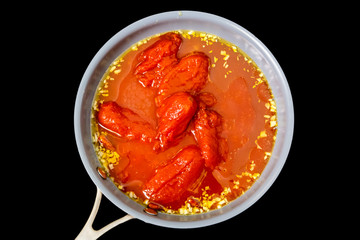 Canned tomatoes, garlic are fried in oil in a frying pan.