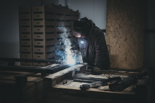  Welder working a welding metal with protective mask and sparks