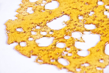 Piece of cannabis oil concentrate aka shatter isolated against w