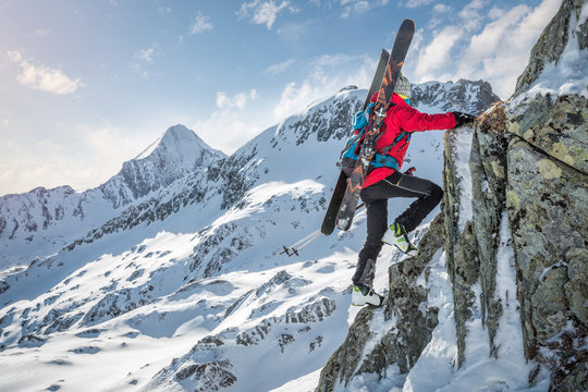 Mountaineer With Skiers Climbing Up A Rock In The Mountains In Winter