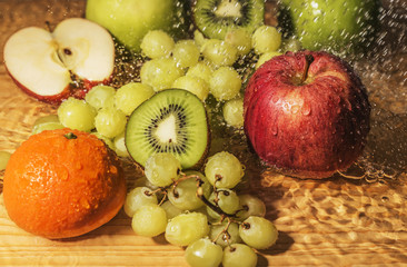 Fresh fruits, apples, kiwi, grapes and mandarin with drops of water