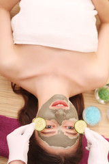 Obraz na płótnie Canvas Spa. Care Facial. Funny young girl with a mask for skin face and cucumbers