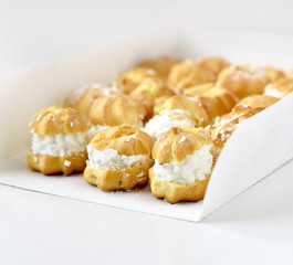 Profiteroles or cream puff cakes in white paper box