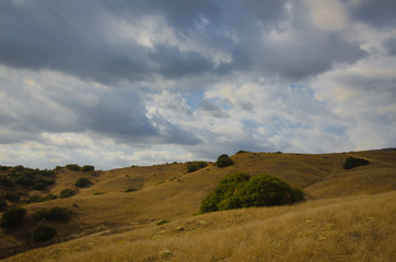Fototapeta na wymiar Grassy brown hills and cloudy sky.