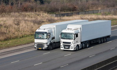 Road transport - two lorries on the motorway driving side to side