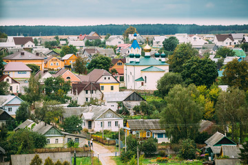 Fototapeta na wymiar Mir, Belarus. Landscape Of Village Houses And Orthodox Church Of The Holy Trinity In Mir, Belarus. Famous Landmark.