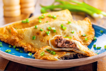Chebureki on a plate. National Ukrainian, Russian, Turkish, Romanian and Tatar food. Meat pastry meal on a table. Close-up shot.