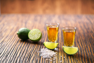 Two shot of gold tequila on a  brown wooden background ,selectiv