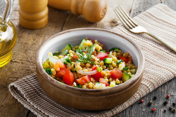 Traditional Israeli healthy meal Ptitim with tomatoes, cucumber and onion for delicious healthy breakfast. Classic Moroccan couscous with vegetables.