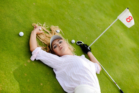 Portrait of beautiful woman relaxing during playing golf on a green field outdoors background