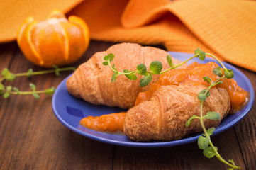 Orange jam and croissants for breakfast. Wooden background. Top view. Close-up