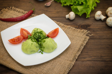 Georgian dumplings Khinkali of spinach dough with meat and tomato spicy sauce satsebeli. Wooden background. Top view. Close-up