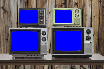 Four Vintage Televisions With Chroma Key Blue Screens and Old Wood Wall