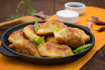 Fried dumplings in the pan. Wooden background. Top view. Close-up