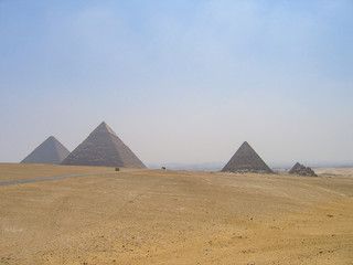 Many tour buses and cars driving on road through great pyramids