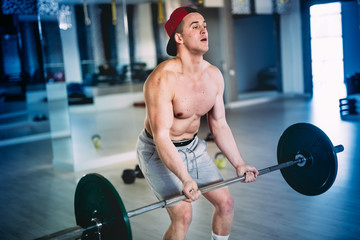 close up portrait of a muscular male, workout with barbell at training facility, at the gym