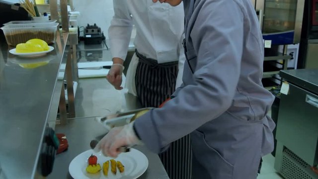 Cook trainee learning to serve vegetables on a plate
