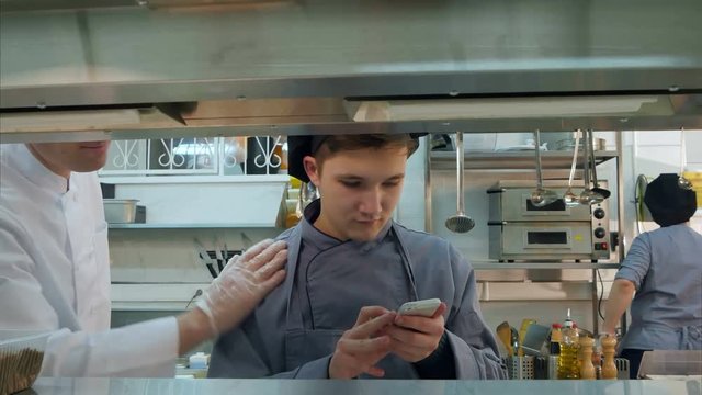 Head chef asking young trainee not to use phone in the kitchen