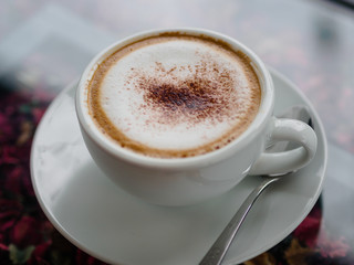 cappuccino coffee on white cut and on glass table with blur background