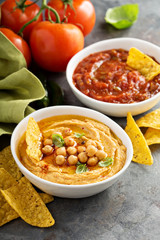 Homemade hummus and tomato salsa in white bowls with chips