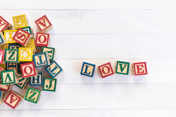 LOVE write in wooden alphabet block on white wooden background.