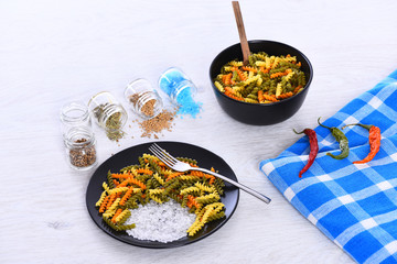 plates with pasta, spoon, chili pepper, spices, fork, tablecloth square