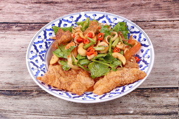 Spicy and sour mixed herb salad with crispy pork served .