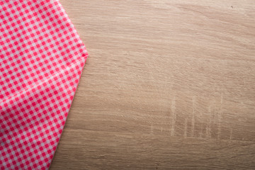 Checkered red and white napkin on wooden background.