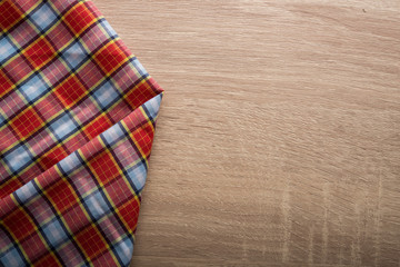 Fototapeta na wymiar Checkered red and white napkin on wooden background.