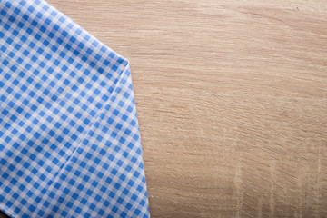 Checkered blue napkin on wooden background.