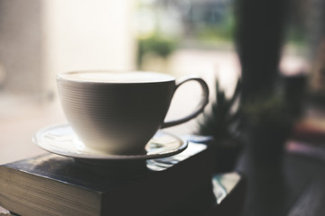 Vintage color Cup of coffee with book in coffee shop.