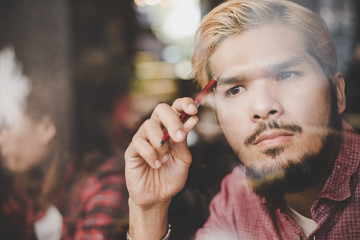 Close up of thoughtful young hipster man while working in cafe.