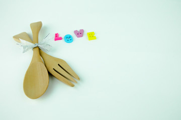 Wooden spoon, wooden fork and colorful letters "LOVE" on white background