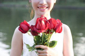 Woman hugging red roses with pleasure.