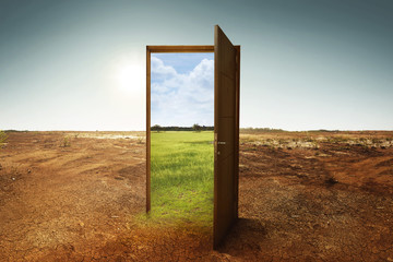 Open wooden door to the new world with green environment - obrazy, fototapety, plakaty