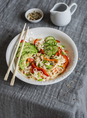 Udon noodles with quick pickled vegetables and avocado on a gray table. Healthy vegetarian food concept