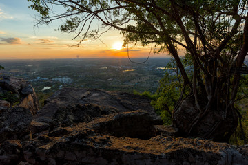 Man traveler is using digital phone on cliff with beautiful landscape sunset over cliff and city  - success concept