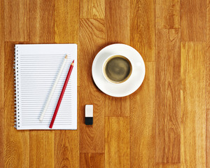Blank notepad with office supplies and cup of coffee on wooden table. Above view.