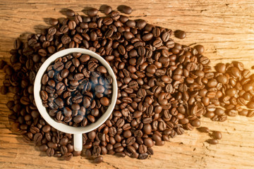 white cup of coffee and coffee bean on wood texture,top view